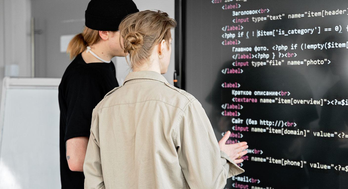 Two developers reviewing code on a large display.